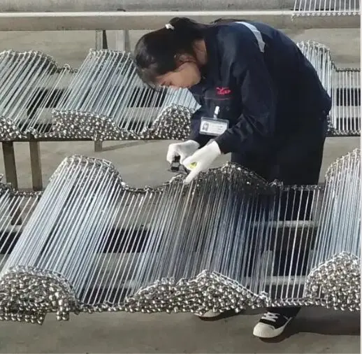 An overview shot of a complete spiral freezer belt system.(https://www.yiyimeshbelt.com/wp-content/uploads/2026/01/spring-freezer-belt-overview.jpg)
Let me explain a little more about these crucial components. Spiral freezer belts are typically made from stainless steel or other high-performance alloys. They are designed for durability and hygiene in demanding environments. We at YIYI Mesh Belt specialize in crafting these robust solutions. These belts feature an open mesh design, which allows for optimal air or heat circulation around the product. This design helps ensure even freezing or heating. The spiral configuration maximizes throughput in a minimal footprint. This makes them highly efficient for industrial applications.
Here is a quick overview of common spiral freezer belt types and their applications:
| Belt Type | Material | Common Applications | Key Features |
|---|---|---|---|
| Balanced Weave Belt | Stainless Steel | IQF, Baking, Roasting | High strength, good air flow, versatile |
| Compound Balanced Weave | Stainless Steel | Heavy-duty freezing, bakery products | Tighter mesh, suitable for smaller products |
| Rod-Reinforced Belt | Stainless Steel | High-temperature ovens, heavy product transport | Very strong, minimal deformation under load |
| Ladder Belt | Stainless Steel | Blanching, washing, light product transfer | Simple design, easy to clean, cost-effective |
Understanding these types helps you choose the right belt for your specific needs, ensuring optimal performance and longevity. From my experience, a well-chosen belt can make all the difference in a busy production facility.
How are Spiral Freezer Belts Manufactured, Anyway?
Are you wondering why some belts perform better than others? The difference often lies in the precision and care taken during the manufacturing process. Poorly made belts can lead to constant headaches and unexpected breakdowns.
Understanding how spiral freezer belts are made reveals why quality control, especially around welds, is so important. This process involves several critical steps to ensure durability and proper function.
The manufacturing of spiral freezer belts is a detailed process that begins with selecting the right raw materials. We primarily use high-grade stainless steel wire. This choice ensures resistance to corrosion and extreme temperatures. The wires are then precisely formed and interwoven to create the specific mesh pattern. This pattern depends on the belt's intended application. After the mesh is formed, individual sections are joined together using welding. This step is critical for the belt's overall integrity and strength. We pay close attention to the welding process because it directly impacts the belt's performance. Our recent investments in advanced machinery, like the stainless steel coil wire drawing machine and round bar drawing equipment, costing USD 400,000 and USD 360,000 respectively, allow us to achieve higher precision in every step. This helps us ensure that the raw materials and finished products meet stringent quality standards.
Here's a breakdown of the key stages in our manufacturing process:
| Stage | Description | Critical Quality Point |
|---|---|---|
| Material Selection | Choosing high-grade stainless steel or other alloys. | Ensuring material purity and appropriate mechanical properties. |
| Wire Drawing & Forming | Drawing raw coils into specific wire diameters and shaping them. | Maintaining precise wire gauge and consistent forming for mesh integrity. |
| Mesh Weaving/Assembly | Interweaving wires to form the belt's structure and pattern. | Achieving uniform mesh spacing and tension across the belt. |
| Welding & Joining | Connecting individual belt sections or components, particularly at edges. | Ensuring strong, clean welds with minimal burr formation. |
| Finishing & Polishing | Smoothing surfaces, removing sharp edges, and cleaning the belt. | Thorough removal of all burrs, sharp points, and surface imperfections. |
| Quality Inspection | Comprehensive checks for dimensions, weld integrity, and overall quality. | Verifying compliance with all design specifications and performance metrics. |
Every stage is important, but the welding and finishing stages are where we focus heavily on preventing burrs, which as you know, can cause many problems down the line.
What are Spiral Freezer Belt Edge Weld Burrs?
Are you experiencing mysterious scratching or black residue in your processing equipment? The culprit might be something you can barely see: a weld burr. These small imperfections can cause big headaches.
Weld burrs on spiral freezer belts are tiny, sharp protrusions of excess material that remain after the welding process. They often occur at the points where individual wires or sections of the belt are joined together.
Let me tell you about the impact of these small but mighty imperfections. When a spiral freezer belt is installed in equipment, especially in a traditional friction-driven system, the inner side welds are constantly under tension. They often press tightly against the equipment's U-shaped bars. If these welds have even minor burrs, the burrs will frictionally rub against the U-bars. This rubbing creates scratches, which deepen over time. As the equipment continues to operate, these scratches on the U-bars generate fine, dark, shaving-like metallic particles. These tiny black residues accumulate and can stick to the weld points. What's worse, at the inlet and outlet of the equipment, these black residues can be blown by cold air fans. This leads to contamination of IQF products, workpieces, or food items. I have seen this cause major contamination events. These events result in significant production of substandard products and severe economic losses. It is a problem that my clients want to avoid at all costs, and so do I.
To further illustrate the potential issues, consider this table showing the direct and indirect impacts of weld burrs:
| Type of Impact | Description | Immediate Consequence | Long-Term Consequence |
|---|---|---|---|
| Mechanical Wear | Burrs abrade against U-bars, causing scratches and metal shavings. | Increased friction, potential for belt sticking. | Premature wear of U-bars, increased maintenance needs, equipment damage. |
| Product Contamination | Metal shavings become airborne and settle on products. | Product discoloration, foreign material presence. | Product recalls, brand reputation damage, compliance issues. |
| Hygiene Risks | Burrs can trap food particles, creating breeding grounds for bacteria. | Difficult cleaning, potential for microbial growth. | Food safety hazards, regulatory fines. |
| Operational Efficiency | Increased friction leads to higher power consumption and potential jams. | Decreased throughput, increased energy costs. | Reduced operational lifespan of equipment, higher overall operating costs. |
| Economic Loss | Costs associated with contaminated products, repairs, and downtime. | Scrap material, immediate financial impact. | Loss of contracts, decreased profitability, long-term market trust erosion. |
This table clearly shows why even a tiny burr is not just a cosmetic issue but a critical operational hazard.
What are the Metal Conveyor Belt Production SOPs to Remove Those Burrs?
Are you concerned about burrs on your conveyor belts impacting product quality? Preventing these issues is all about having a robust, standardized manufacturing process. Without clear procedures, you're leaving quality to chance.
At YIYI Mesh Belt, we have established strict Standard Operating Procedures (SOPs) specifically designed to eliminate weld burrs and ensure the highest quality of our metal conveyor belts. These SOPs cover every stage of production where burrs might occur.
![A worker carefully finishing and inspecting a metal conveyor belt.