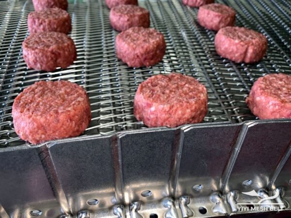 Meat patties on a metal conveyor belt in a freezing line